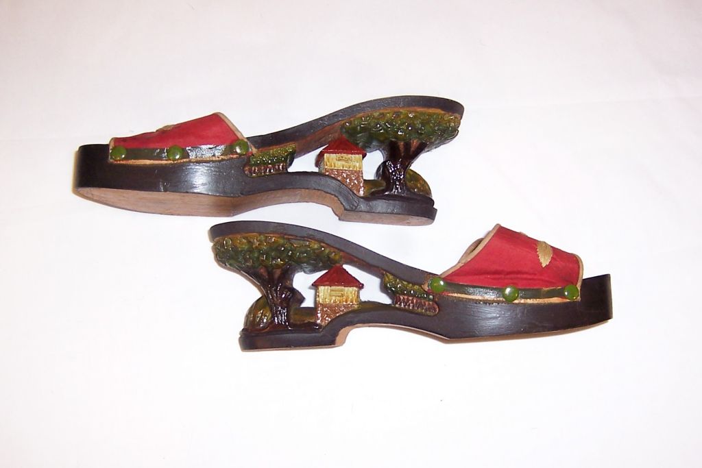 This is a fabulous pair of hand-carved wooden shoes, of the 1940's vintage, from the Philippines. The heel of each shoe has been masterfully hand-carved and painted. The top part of each shoe is covered in red embroidered silk. Each shoe measures 8