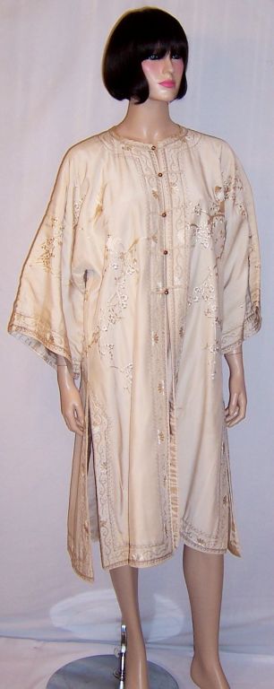 This is a handsome, 1920's vintage, Japanese hand-embroidered, white on white robe. The embroidery, which has been masterfully executed, depicts birds with black beaks positioned on plum blossom branches. The robe has five brass buttons for closure,