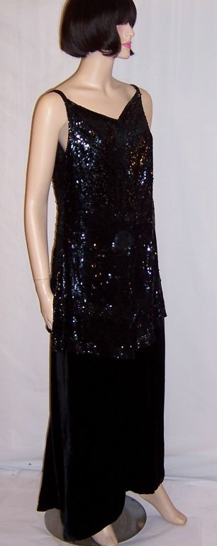 Offered for sale is this gorgeous, early 1920's, black silk velvet gown with an attached, meticulously sequined and beaded, sleeveless tunic top. The seeveless tunic top has a flattering V-neckline and a scooped-out back. The gown must be slipped