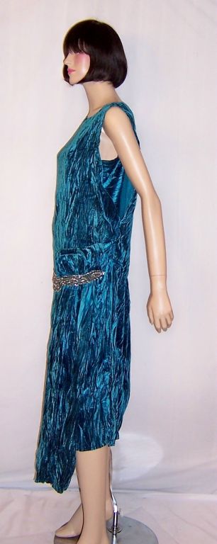 This is an exceptionally gorgeous, early 1920's vintage, turquoise crushed silk velvet gown with a dropped waist, which has been beautifully accentuated with a beaded and jeweled waist band, and a bow and long sash on the left side of the gown. The