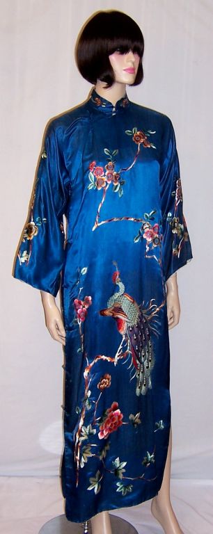 This is an extraordinarily beautiful chic cheongsam gown lavishishly hand-embroidered with peacocks, peonies, and plum blossoms. It is not in mint condition, but in remarkably good vintage condition. There are some flaws in the teal silk, a few tiny