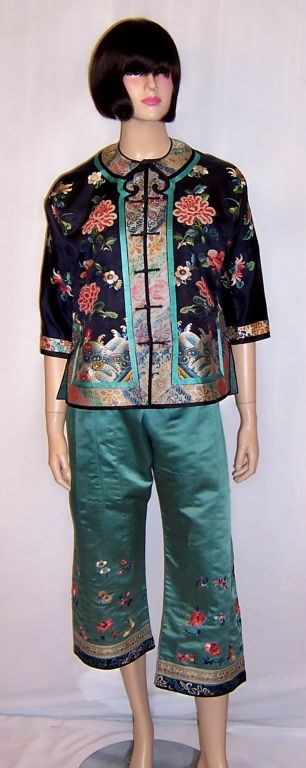 This is an extraordinarily lavishly embroidered, Chinese, navy and teal colored silk jacket and matching pants in excellent vintage condition. The set dates to the very early 20th century and could possibly be one hundred years old. The red peonies