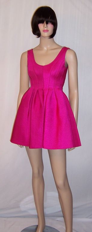This is an unusual and early Donna Karan design created for her DKNY line made of 100% rubber and coated with nylon. Definitely designed for the younger set in mind, this cerise-colored modified baby doll dress, without the frills and fussiness, is