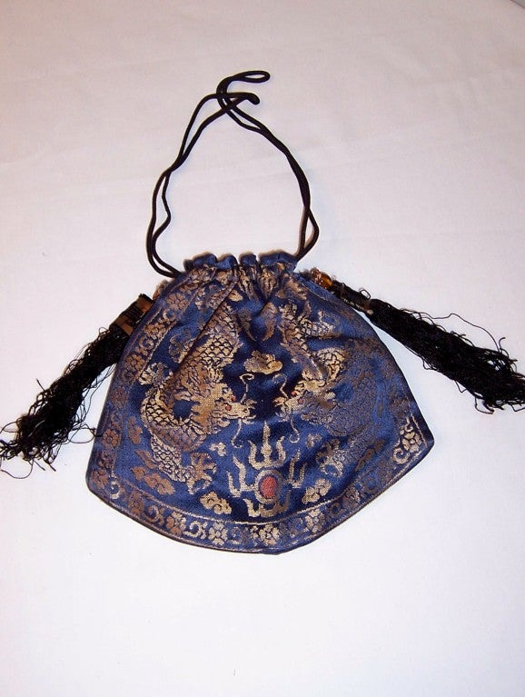 This is a 1920's vintage, Chinese jacquard-weave brocade, draw-stringed purse depicting two five-toed dragons. The purse has two Chinese tassels, each attached to a carved glass amber-colored bead and it is in excellent vintage condition.