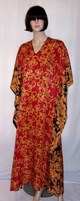 This is a striking red, gold, and black printed caftan of the 1980's vintage, designed by Ruth Norman for Neiman Marcus. The main portion of the caftan has an all-over repeated pattern print in red and gold and a slightly different all-over repeated