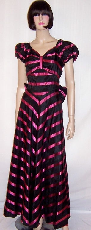 Offered for sale is this early 1940's, dramatically stunning black and magenta taffeta striped gown, beautifully constructed to flatter the figure. The gown has a very becoming sweetheart neckline, a fitted bodice, a side zipper for closure, poofy
