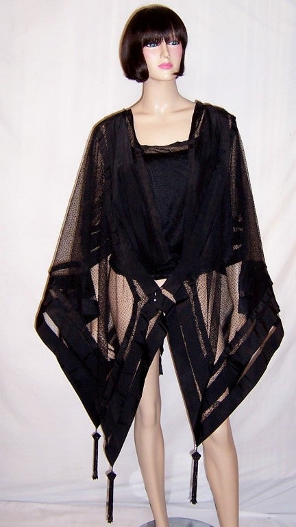 Offered for sale is this unusually rare and unique black Victorian bodice with attached cape made of sturdy netting with a dramatic handkerchief hemline trimmed in wide grosgrain ribbon and embellished with four long beaded tassels. The bodice is
