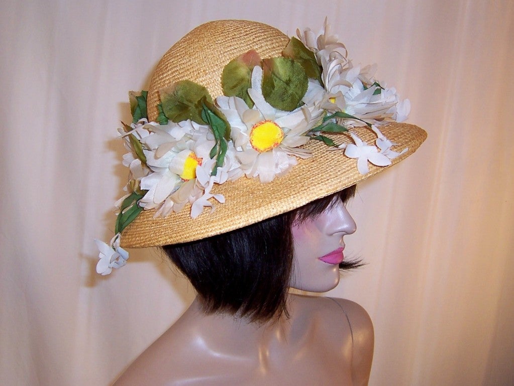 This is a lovely springtime Christian Dior Chapeaux made of fine natural straw with a wide brim which has been decorated with large white shasta daisies. The label is present and in tact and reads Christian Dior Chapeaux Paris-New York for Lord &