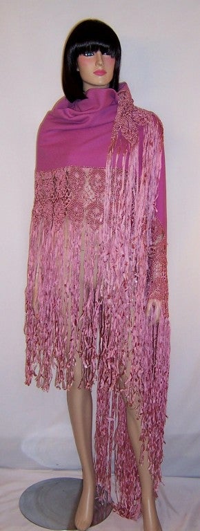 This is a luxurious and vibrant orchid colored woolen shawl embellished with intricate silk macrame work and long fringe. The shawl is rectangular in shape and measures 55