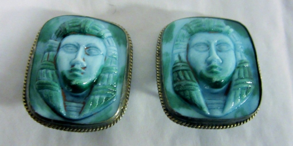 This is a stunning pair of Egyptian Revival, turquoise and green mottled, poured glass earrings, each depicting the head of a pharaoh in bas-relief. Each rectangular-shaped glass stone is encased in a fine silver-toned chain type of bezel. Each