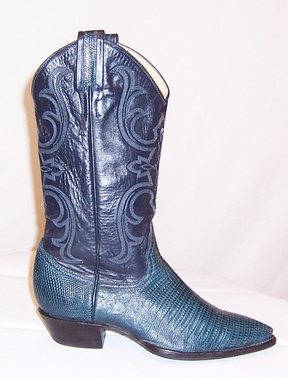Offered for sale is this fantastic pair of teal green lizard and black tooled leather cowboy boots by Larry Mahan. The boots have been handcrafted in El Paso, Texas, have pointed toes, a 1 1/2