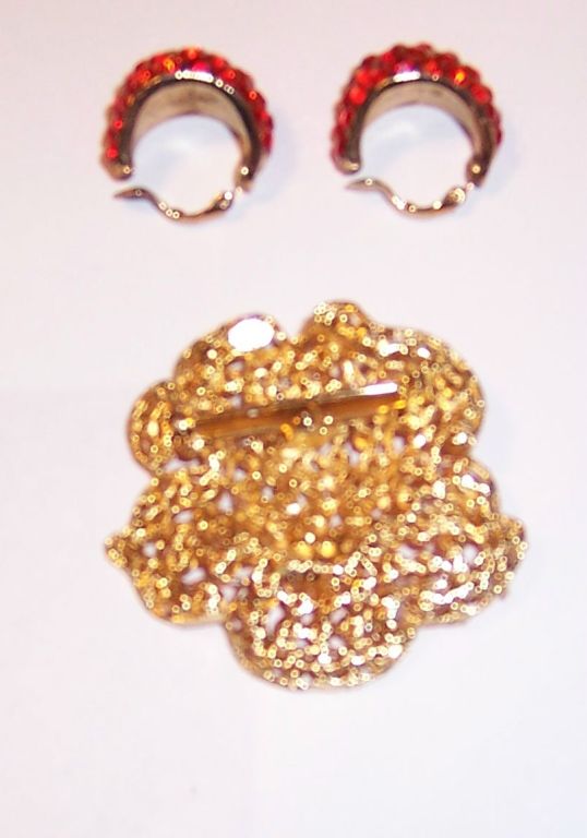 This is an unusual floral brooch and earring set by Weiss set with brilliant orange stones on a gold-tone backing and stamped 