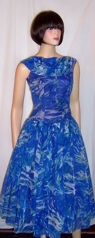This is a show-stopping 1950's floral printed cocktail dress by Klever Klad of Toronto in the vibrant colors of cobalt blue, turquoise,and white. Klever Klad of Toronto had been in business from 1941-1955. This stunning dress has a fitted sleeveless