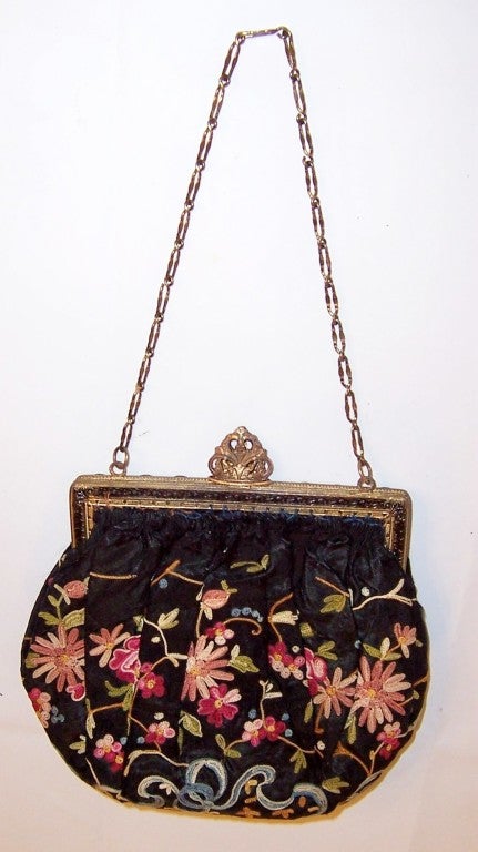 This is an handsome 1920's vintage, black silk bag lavishly embellished with tambour embroidery depicting flowers, vines, ribbon, and bows. Tambour embroidery is a continuous worked chain stitch formed with a tambour hook which forms a loop similar