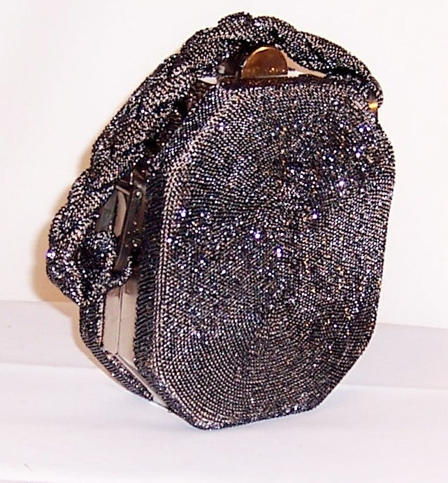 This is an unusual charcoal gray glass beaded, octogonal-shaped, bag with a heavy braided handle, a silver-toned clasp and frame, of the 1940's vintage. Its label is present and in tact and reads, M.E.Product 