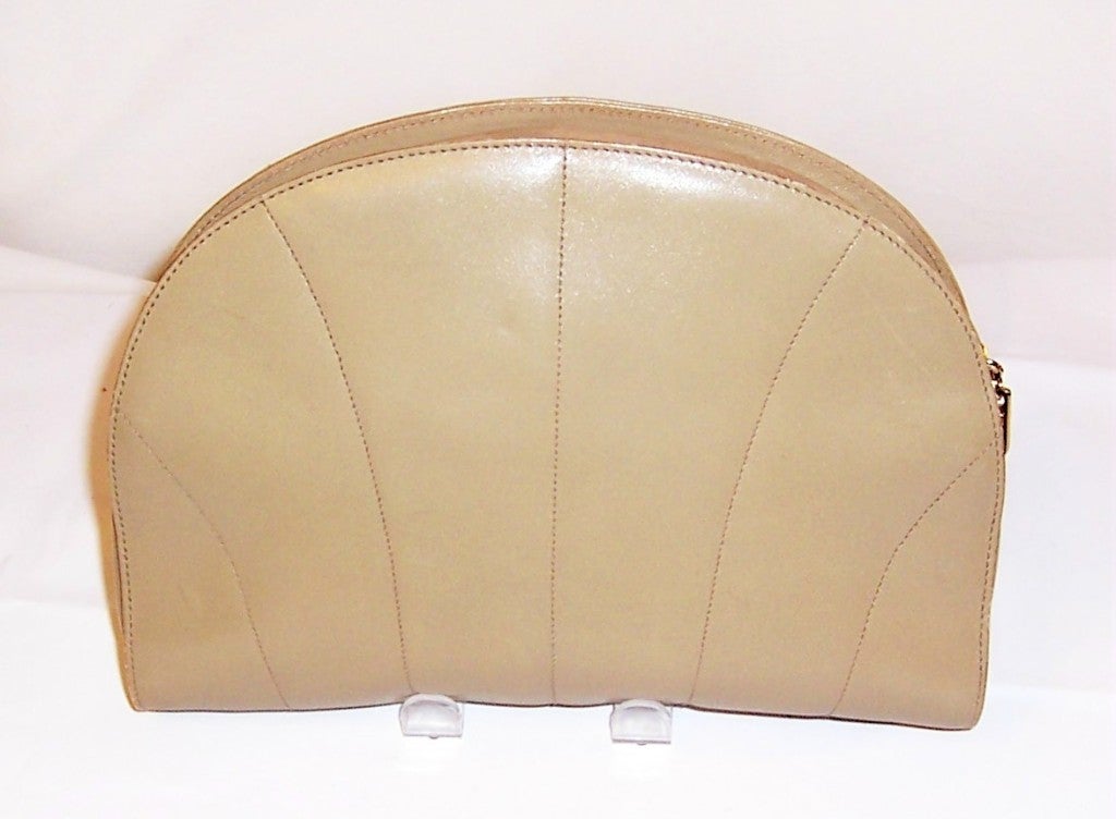 This is a chic and luxurious tan, shell-shaped clutch bag with a zippered closure by Salvatore Ferragamo. Ferragamo is a Florence based, family-owned company and has been synonymous with Italian luxury for over 75 years. This lovely clutch/pouch bag
