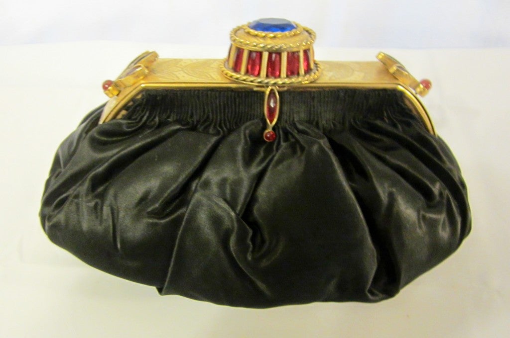 Offered for sale is this uniquely unusual, jewel embellished black silky satin, pouch-styled evening bag with its elaborate frame and clasp. The frame and clasp of this handbag set it apart as being a precious work of art and not just an ordinary