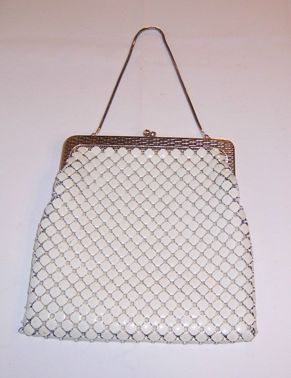 This is a handsome 1960's vintage, white enameled metal mesh bag by Whiting & Davis with a silver-toned frame, kiss clasp closure, and a thin gas pipe snake chain. It measures 7