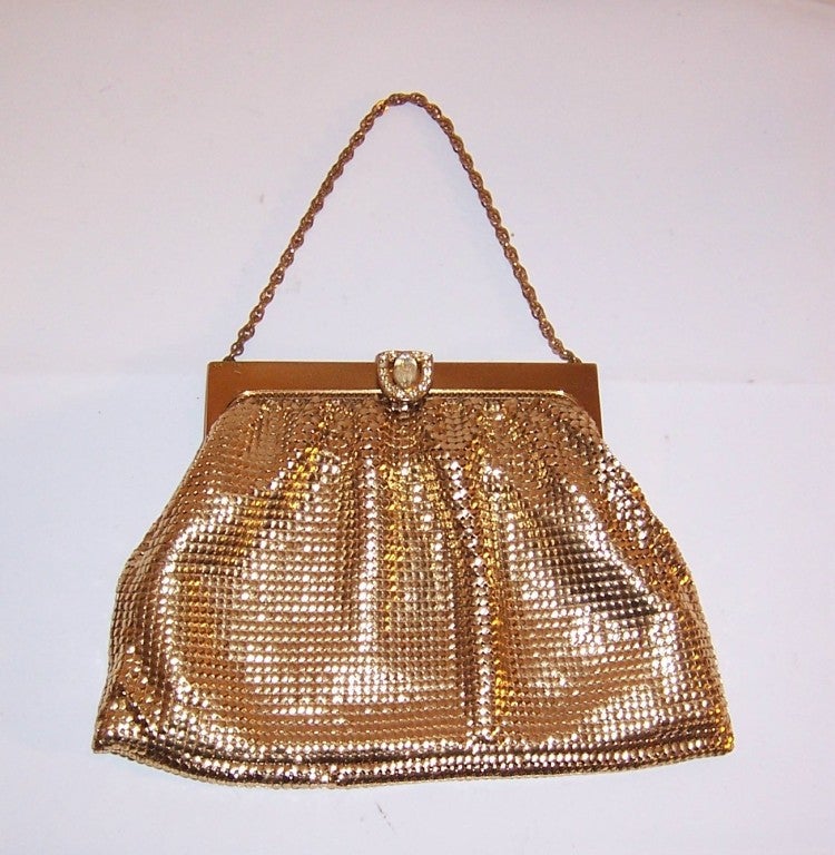 This is a 1950's vintage, gold metal mesh evening bag with a clasp comprised of one large marquis-shaped rhinestone surrounded by tiny clear rhinestones in a gold toned mounting. Whiting & Davis is stamped in the frame's interior and there is also a