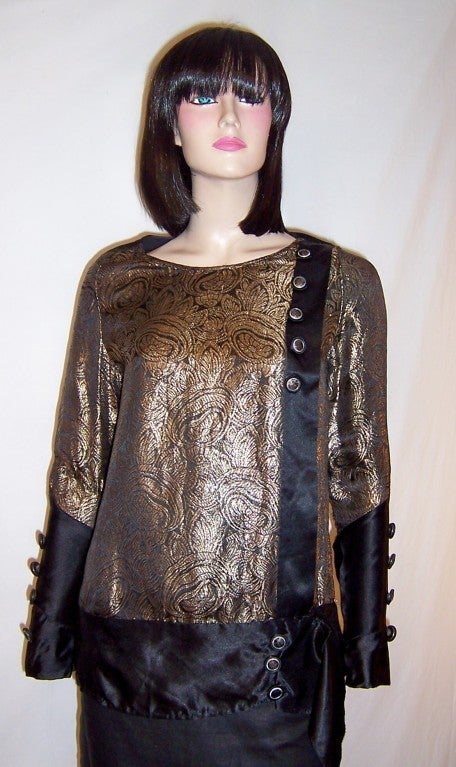 This is an exceptionally beautiful, 1920's vintage, black silk and gold lame blouse with stylized floral designs which were so indicitive of the Art Deco period. The blouse is long and tunic-like with a rounded neckline and is accentuated with a