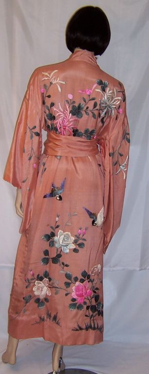 This is a beautifully hand-embroidered, 1920's vintage, apricot silk kimono with matching sash. The elaborate embroidery is executed masterfully and depicts chrysanthemums, roses, and bluebirds. The kimono is in very good vintage condition with the