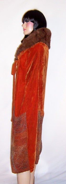 This is a wonderfully dramatic and decorative burnt sienna velvet opera coat/cape, which has been embellished with glass beadwork designs. The cape is of the 1920's vintage, has a full fur collar, and has been lined in a silk crepe fabric. It has