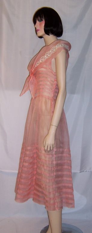 This is a lovely, lightweight pink organdy, summertime dress with a modified sailor collar and white lace appliques. There is a side zipper for closure, which most likely had been added at a much later date for easier accessibility. The interesting