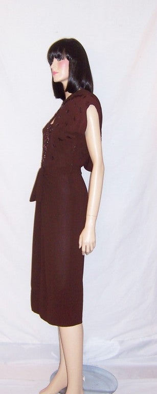 This is a charming and delightful 1940's vintage, brown crepe sequined dress with short sleeves, a fitted waist line, a straight skirt, a side zipper for closure, an attached hood trimmed in sequins, all characteristic 1940's design elements.  The