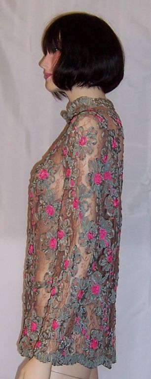 This is a fancy and whimsical blouse whose anonymous designer has mastered the technique of making flowers out of silk ribbon. The bright pink centers against the teal green petals make a pleasing color combination against the mocha lace background.