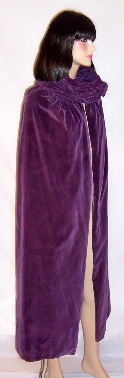 This is a dramatic and lovely 1920's vintage, violet velvet capeor cloak with an ample and masterfully ruched collar and a single hook and eye closure at its neckline.  Its label is in tact and reads  Bourne & Hollingsworth Ltd. Oxford Street