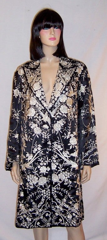 This is an extraordinarily beautiful, 1920's vintage, black and white Chinese silk coat elaborately embroidered with fauna, flora, and birds.  The coat is single-breasted with two fabric covered black buttons for closure. It measures 21