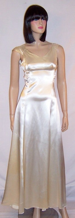 Offered for sale is this exquisitely plain white satin gown with slightly capped sleeves and interesting detailing including modified pleating techniques and the use of yokes.  The gown is a Size XS with a back zipper for closure.  It has a
