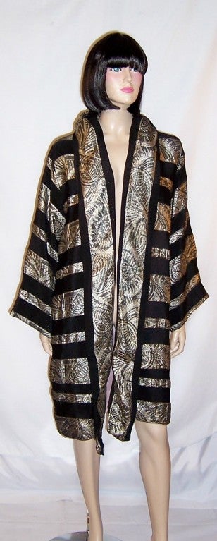 Offered for sale is this strikingly elegant 1920's Art Deco, silver lame and black silk evening/opera coat with alternating bands of black silk and silver lame running horizontally and vertical bands of the same running around the collar and down