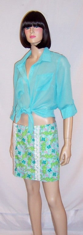 This is a fanciful Lilly Pulitzer, green and turquoise printed alligator, hip-hugger skort, a cross between a skirt and shorts made of crisp cotton and trimmed with two lines of white lace, running vertically. It is marked a Size 4 and is in
