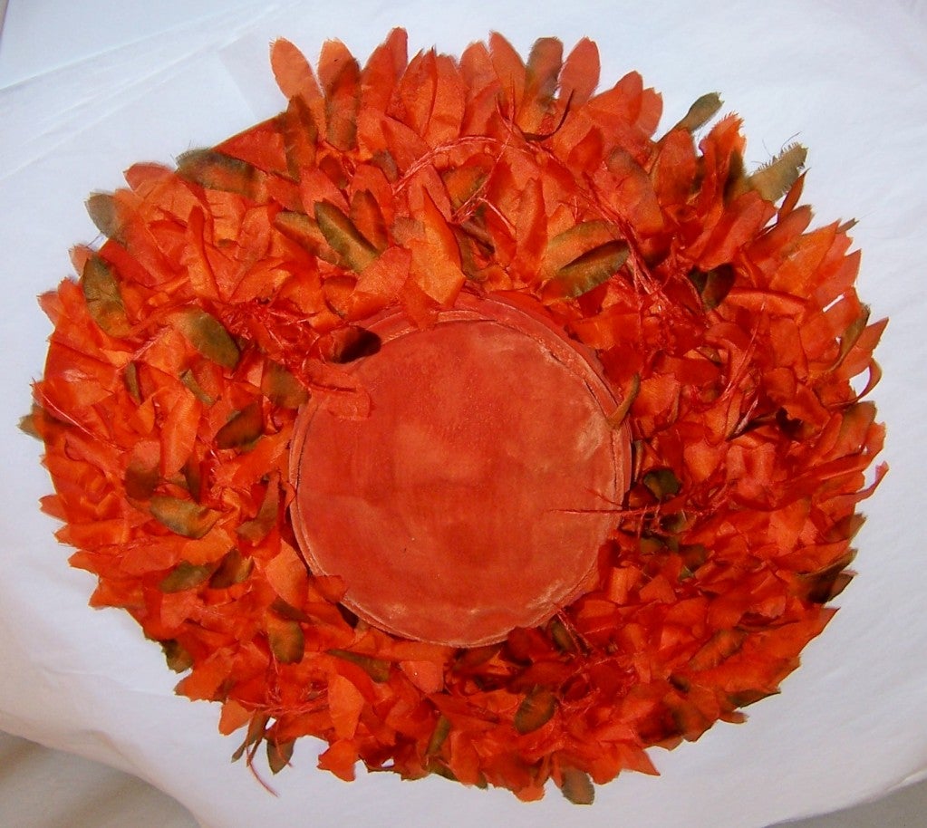 This is a gorgeous and unusual orange velvet cartwheel hat embellished with orange silk flowers surrounding the entire brim.  The brim measures 4 1/2