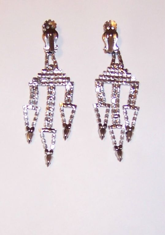 This is an extraordinarily beautiful pair of 1960's vintage<br />
clear rhinestone earrings. The earrings are clip-ons and are unmarked. Three stylized arrows hang from the base of each earring. Each earring measures 1.5