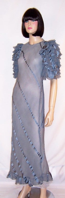 This is a gorgeous 1930's vintage, periwinkle blue silk chiffon and satin evening gown which exudes femininity and sensuality.  The gown is cut on the bias and its diagonal matching stripes and elaborate ruffle treatment of the sleeves exhibit