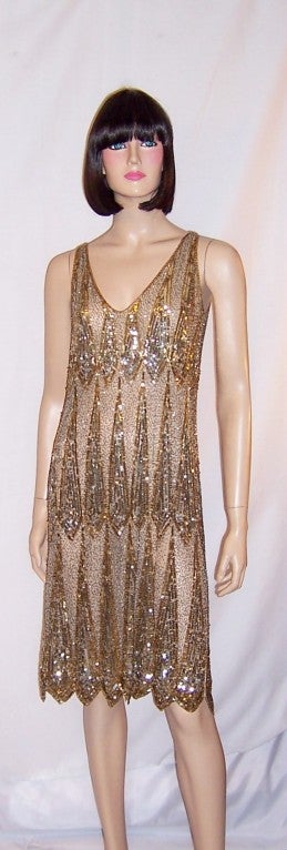 Offered for sale is this striking gold and silver sequined and beaded dress of the 1920's vintage with a flattering V-neckline in the front and a scooped-out neckline in the back.  The dress must be slipped over one's head to be worn, as there are