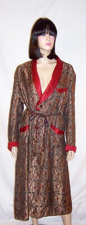 This is an handsome men's Art Deco lounging/smoking robe of brocaded fabric in black, gray, burnt sienna, and white trimmed in burgundy satin with its original fringed belt. The robe is in very good vintage condition with  an old repair to the back