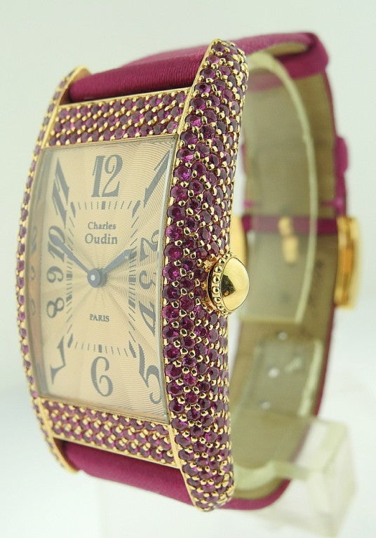 This is a French rectangle ladies wristwatch 18kRG'Charles Oudin' Paris with rubies. It has 18k rose gold curved case, encrusted by rubies and dark pink satin band with 18k rose gold factory buckle. With quartz movement and sunburst dial.