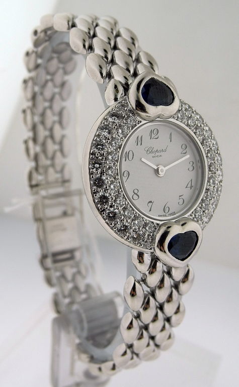 This is Chopard ladies 18k white gold bracelet watch with full diamond case and cabochon heart shaped sapphires. White dial with black Arabic numerals. Dial and bracelet signed Chopard, Geneva.