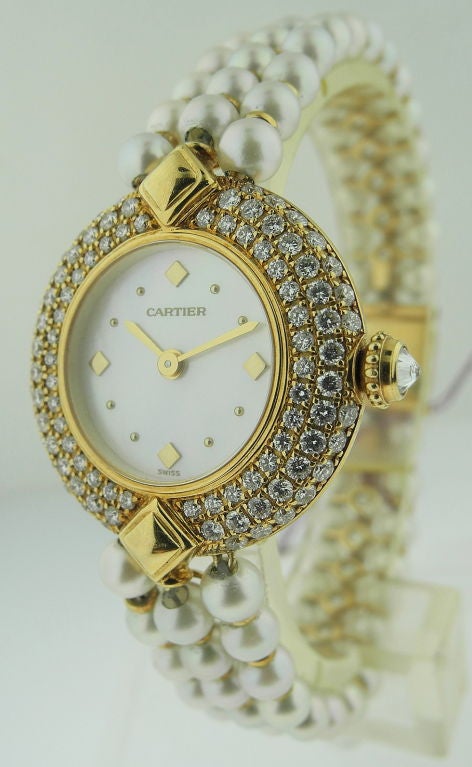 This is a Cartier very fine and elegant 18k yellow gold ladies wristwatch. Quartz movement.  MOP Dial ,Comes with Cartier integral set of pearls bracelet and triple diamond case.