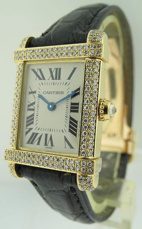 This is a Cartier Tank Chinoise W80199 watch. It has a 19x30.8mm (with lugs) yellow gold set with diamonds case, a silver dial with Roman numerals, a leather strap with Cartier rose gold deployant buckle and a quartz movement. The watch is