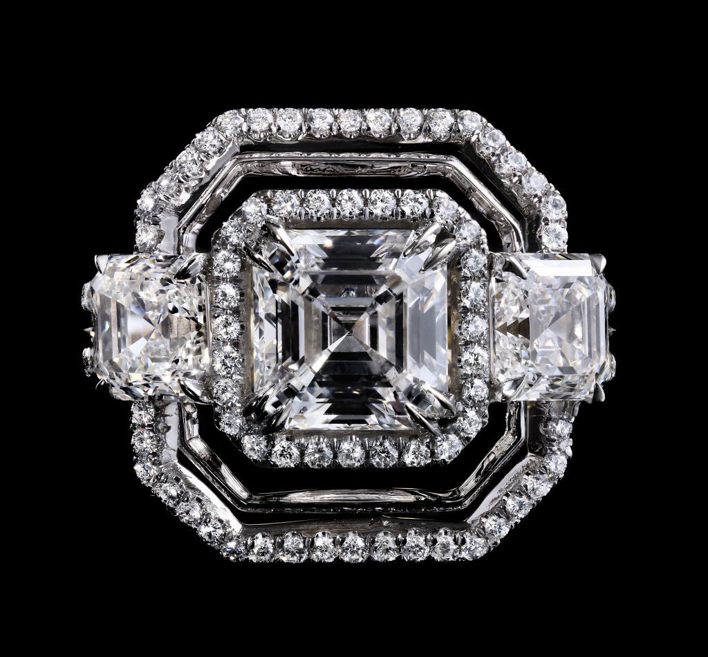 This three-stone Diamond ring features a 2.10 carat Asscher-cut Diamond center stone flanked by a pair of matching Asscher-cut Diamonds totaling a 2.02 carats, and surrounded with Alexandra Mor's signature knife-edged octagon wire and a double band
