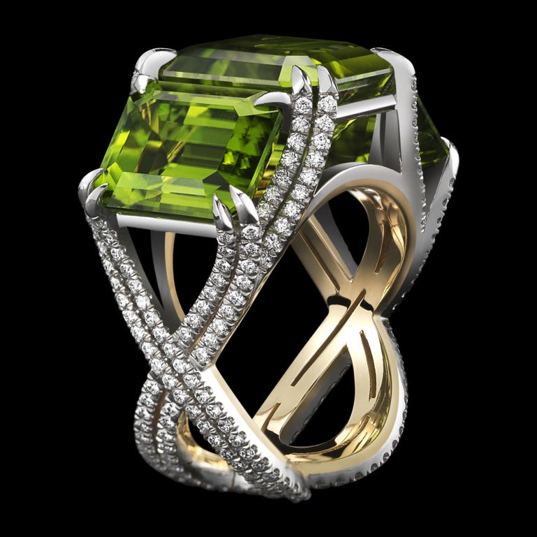 A three-stone emerald-cut Peridot ring totaling 21.04 carats, set with intricate intertwined bands adorned with Alexandra Mor's signature details of 262 ‘floating’ Diamond melee and knife edged double spit prongs. Platinum set on 1mm 18-karat yellow