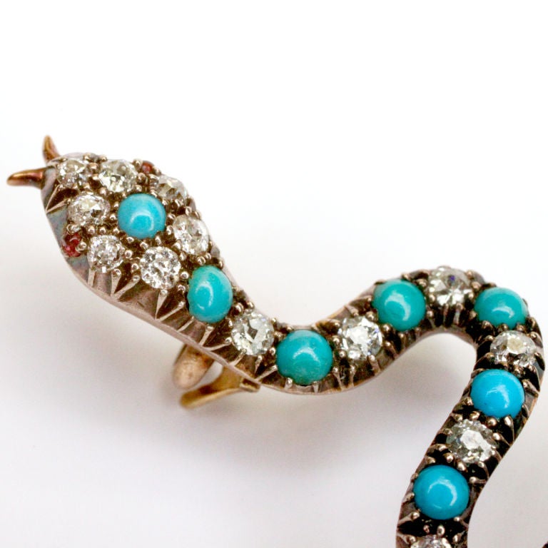 Charming antique snake brooch with alternating diamonds and turquoise beads mounted in gold.  Tiny cabochon ruby eyes with gold forked fangs!  22 diamonds and 17 turquoise beads.