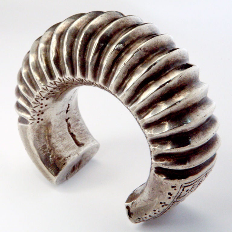 Large Indian silver cuff bracelet designed with high grooved ridges and engraved leaf pattern detail.