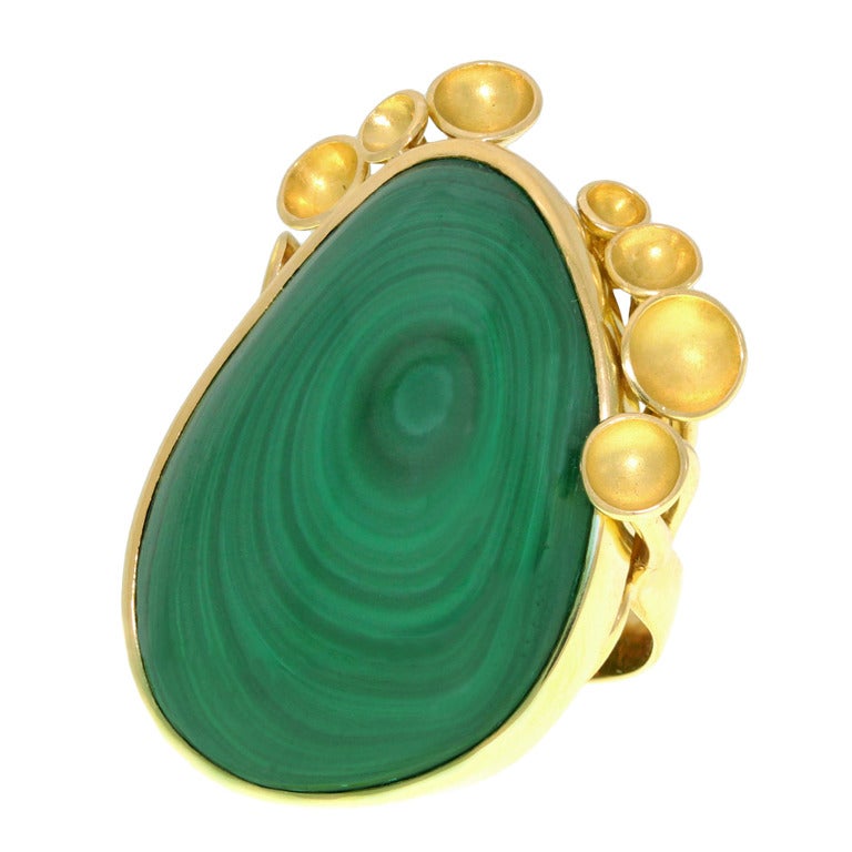 CIRCA 1960-70er Jahre, 18k, Schweiz. Dieser einzigartige Ring mit seinem wunderschön gemusterten Malachit stellt eine surreale Landschaft dar, die von Ranken und Schotenpflanzen gesäumt wird, die um die Ränder lugen. Seine traumhafte Annäherung an