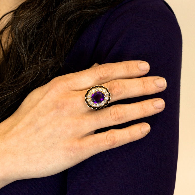 This 14k yellow gold Victorian ring has a finely detailed scalloped gallery trimmed with black champlevé enamel and set with 14 glittering white diamonds (1.65 carats H-I color, SI1-2 clarity) around a vivid 4.5 carat amethyst. Finely constructed