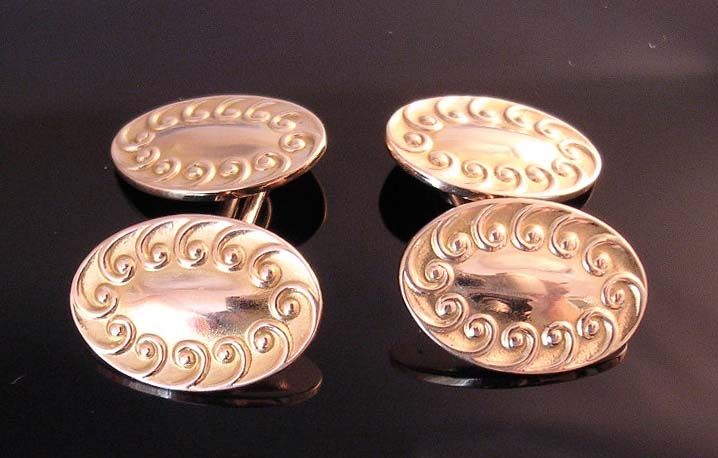 Cufflinks of Art Nouveau design, each double-sided 14k gold links bordered by raised scrolls. The backs are connected by oblong gold chain links for easy wear and security.

Circa 1920.

Each oval link: 3/4 in (2 cm.) long. Distance between links-1